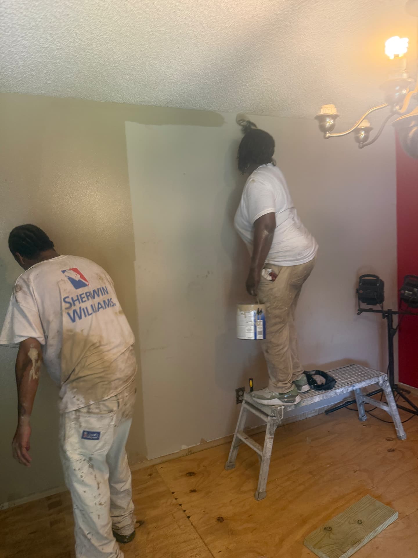 Students painting a corner wall from a step platform