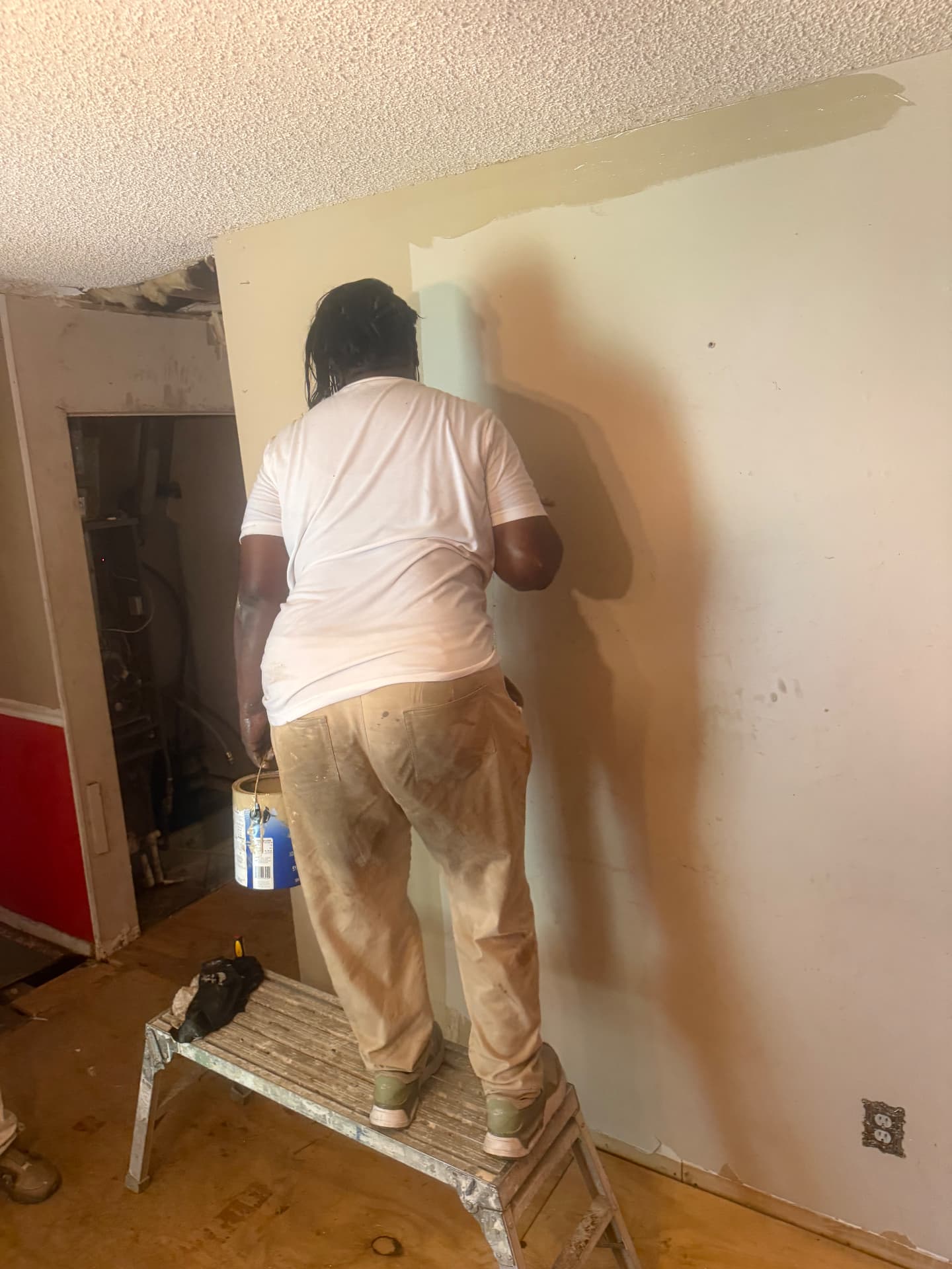 Student applying primer to a prepared interior wall